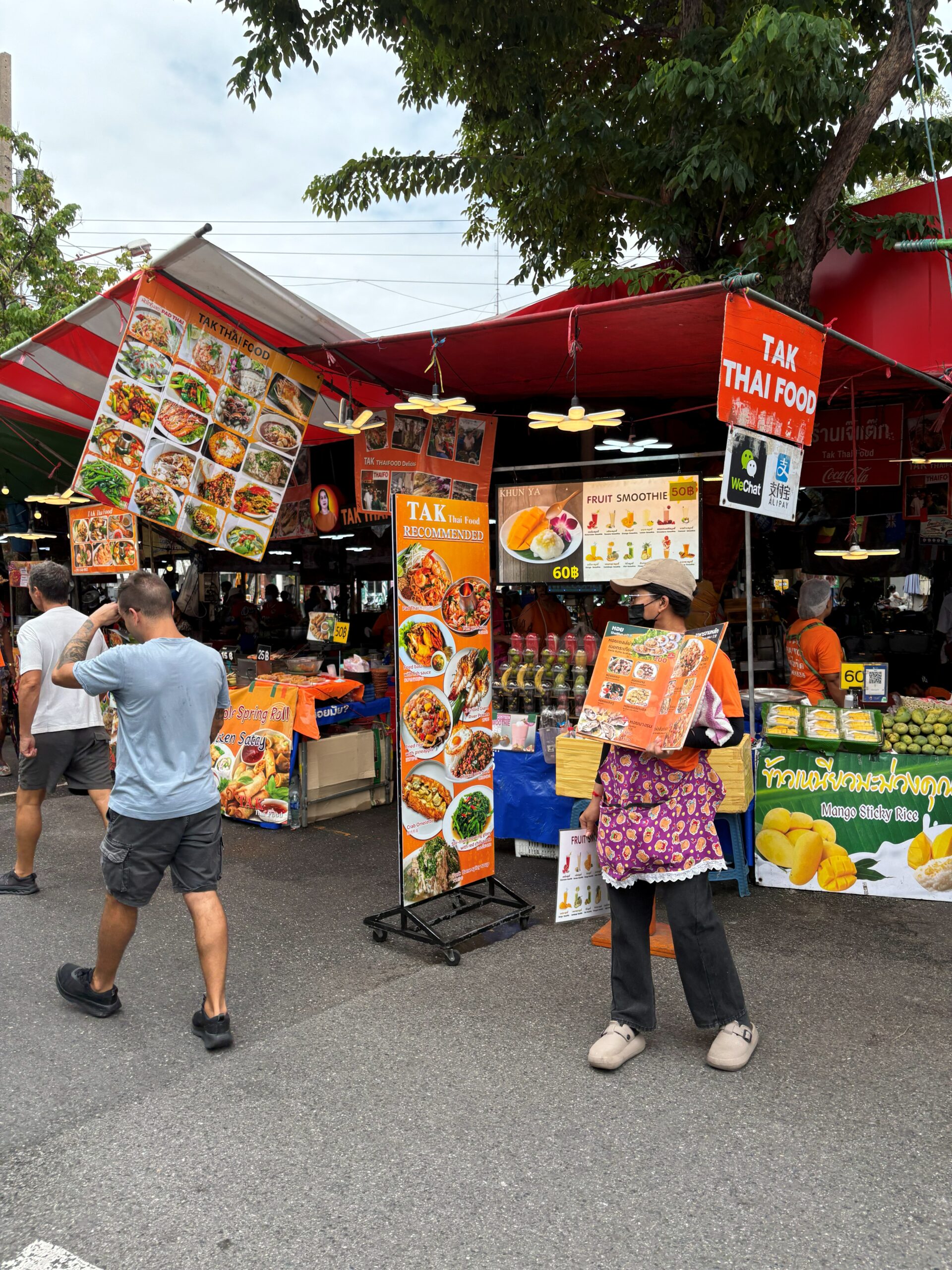 「TAK Thai Food」という看板を掲げた屋台とメニュー看板