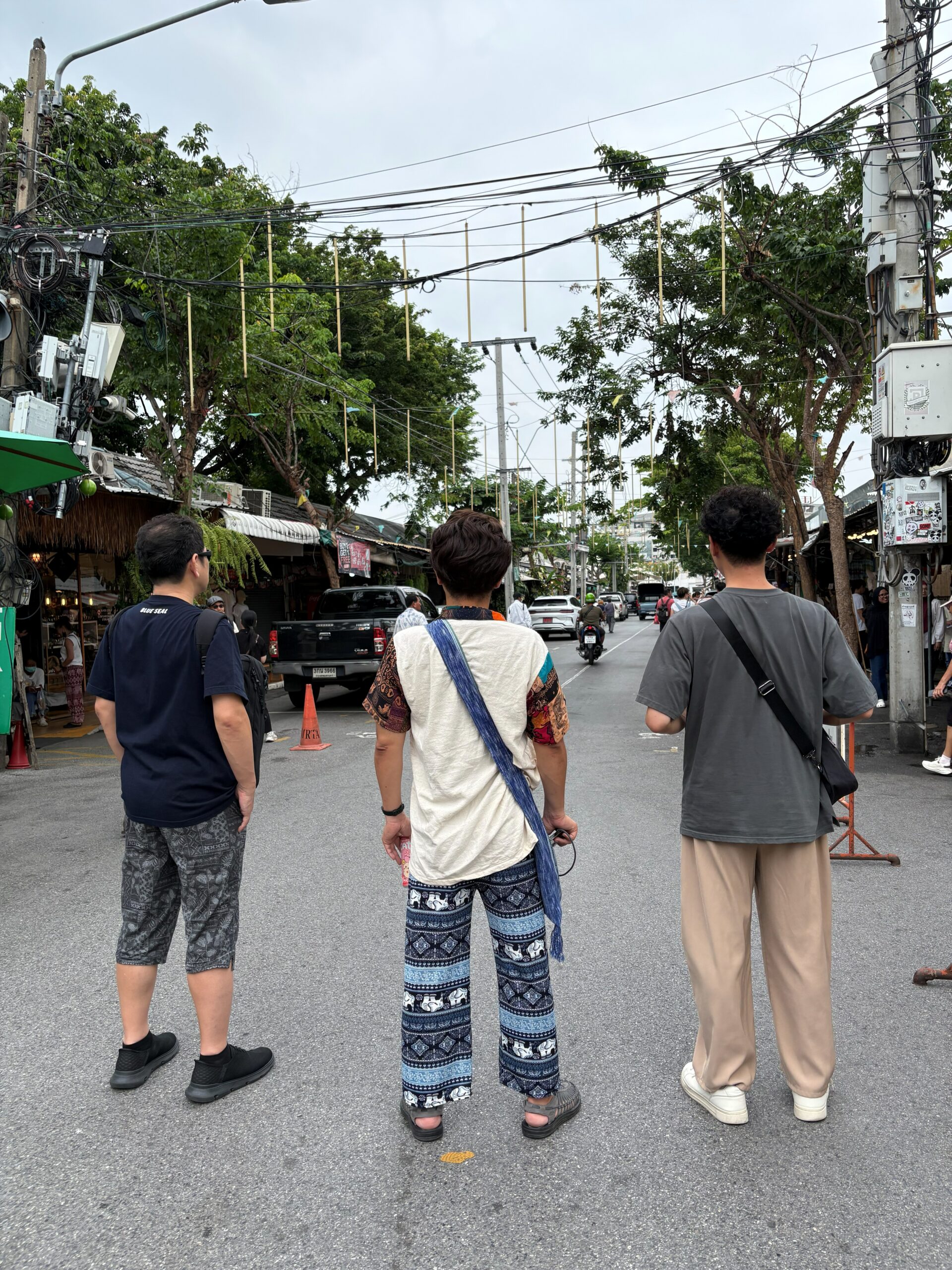 路上に立ち、通りの先を眺める参加者3名の後ろ姿