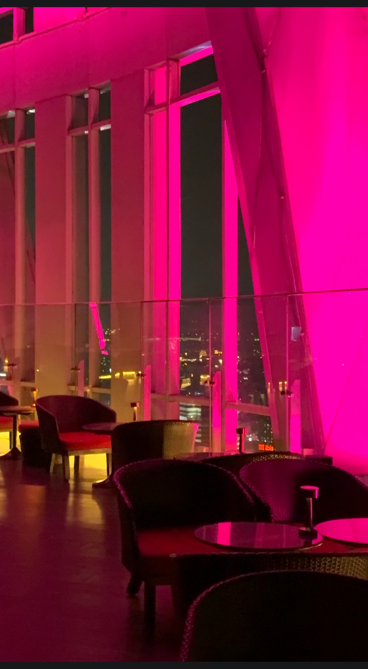 ピンク色にライトアップされたラウンジ席と夜景