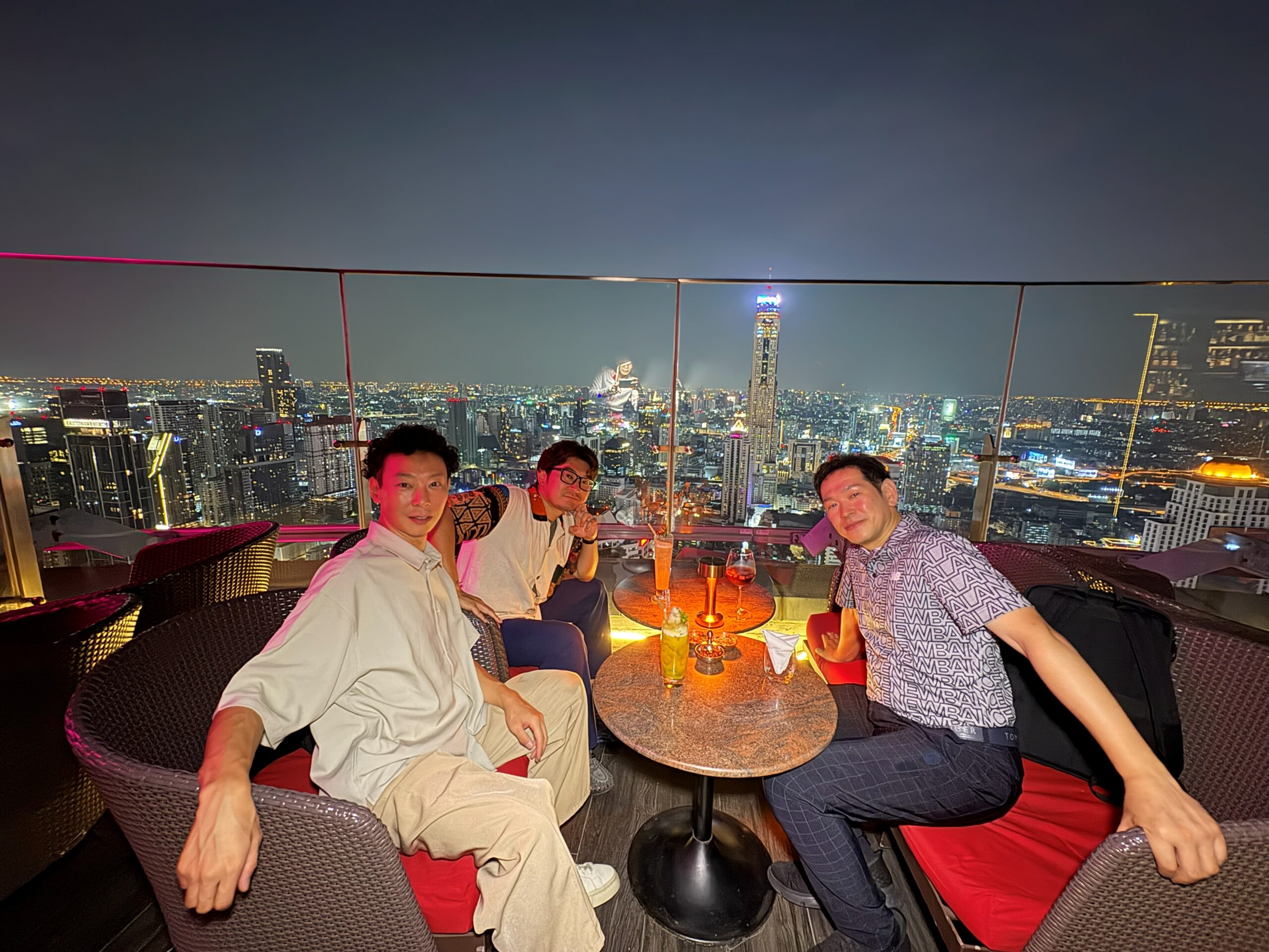 Red Sky Barのソファ席で夜景を背に並んで座る3人